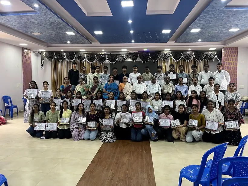 Large group of students holding certificates in the school auditorium at the felicitation ceremony