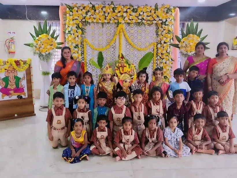 Children and teachers gathered on a floral-decorated stage for a festival celebration