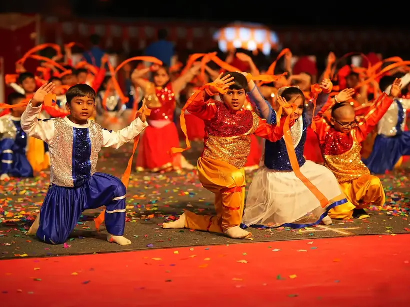 Students in colourful folk costume performing a group dance
