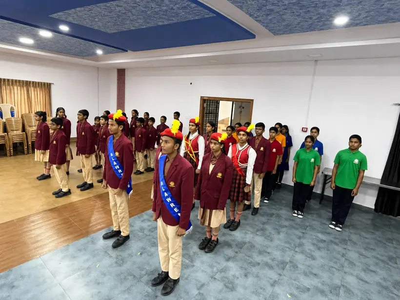 High school students in maroon blazers standing in formation at assembly, with house captains wearing sashes