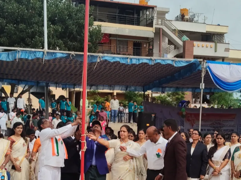 Chief guest hoisting the national flag on the school ground, with a tricolour rangoli at the base of the mast