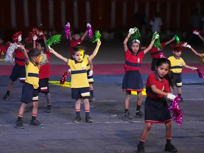 Young children in school uniform performing a stage display with pom-poms