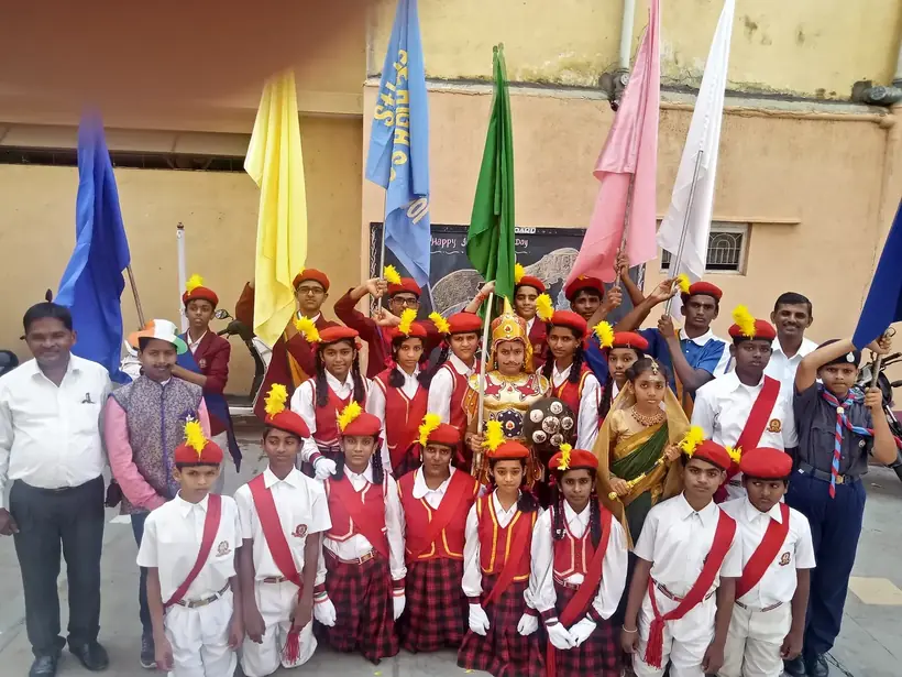 Bharat Scouts and Guides students in uniform holding troop flags outdoors