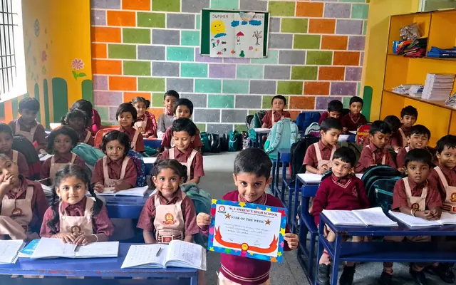 Primary students at their desks in a brightly decorated classroom, one holding a Star of the Week certificate