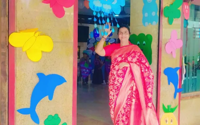 A staff member in a pink saree at the school entrance, decorated with dolphin, fish, frog and cloud cutouts for Colour’s Day