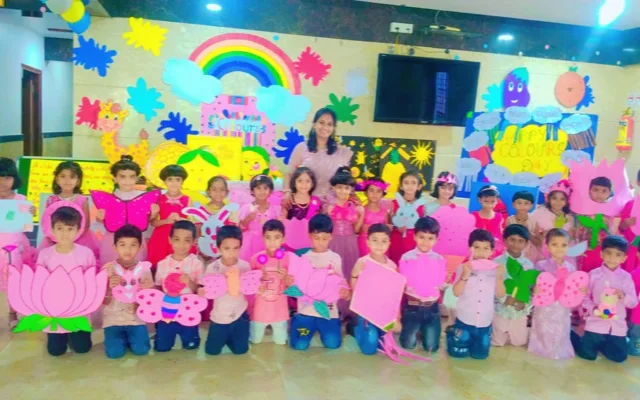 A teacher smiling with her class, all dressed in pink, for Colour’s Day