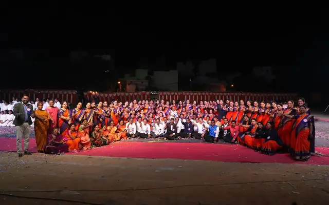 Large group of school staff and students gathered outdoors in traditional dress