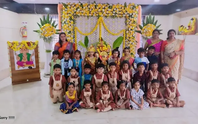 Children and teachers gathered on a floral-decorated stage for a festival celebration