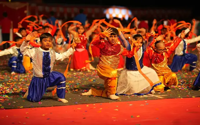 Students in colourful folk costume performing a group dance