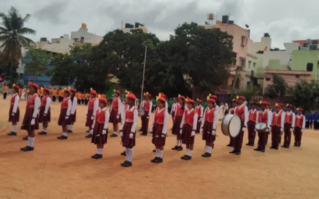 A student contingent in maroon and white standing to attention in formation for the march past