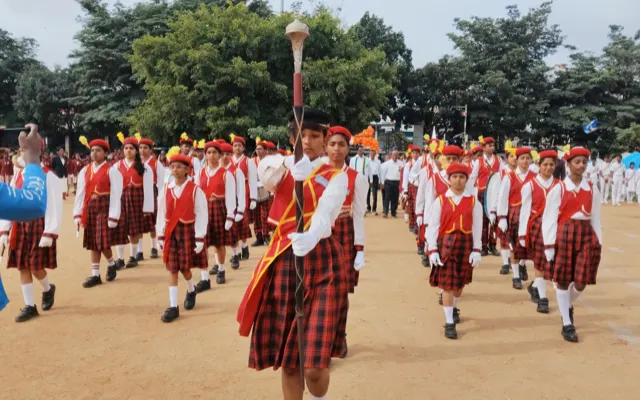 The school band in red tartan uniform leading the Independence Day parade, drum major with mace at the front