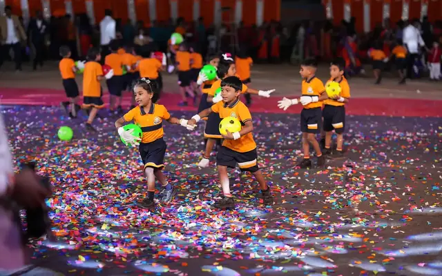 Primary children in sports uniform performing a mass ball display