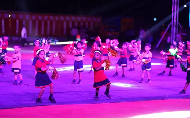 Children in costume dancing on stage under coloured lights