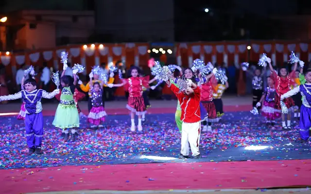 Young children performing a group display on a brightly lit stage