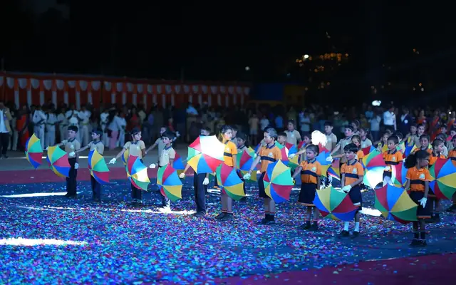 Large group of students performing a coordinated umbrella display at night