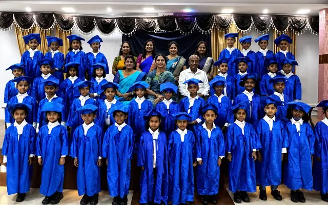 Nursery Wing children in blue graduation gowns and caps with their teachers
