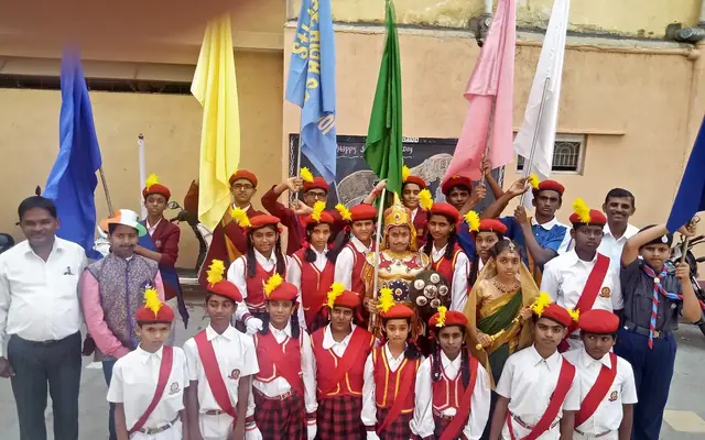 Bharat Scouts and Guides students in uniform holding troop flags outdoors