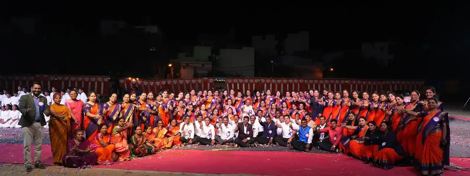 Large group of school staff and students gathered outdoors in traditional dress