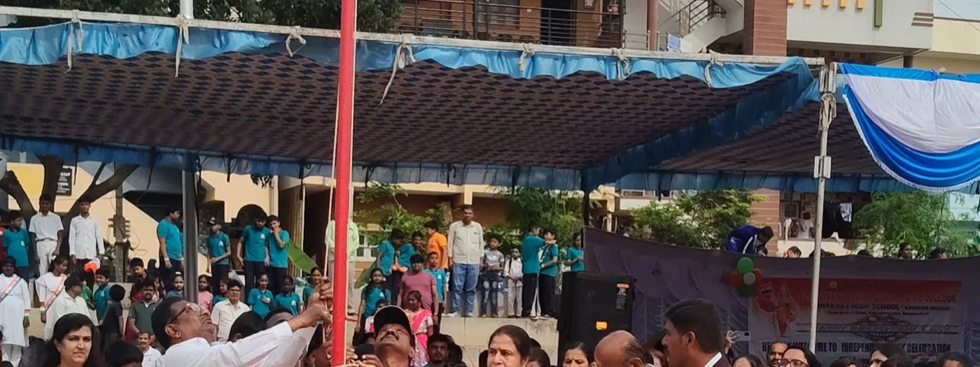Chief guest hoisting the national flag on the school ground, with a tricolour rangoli at the base of the mast